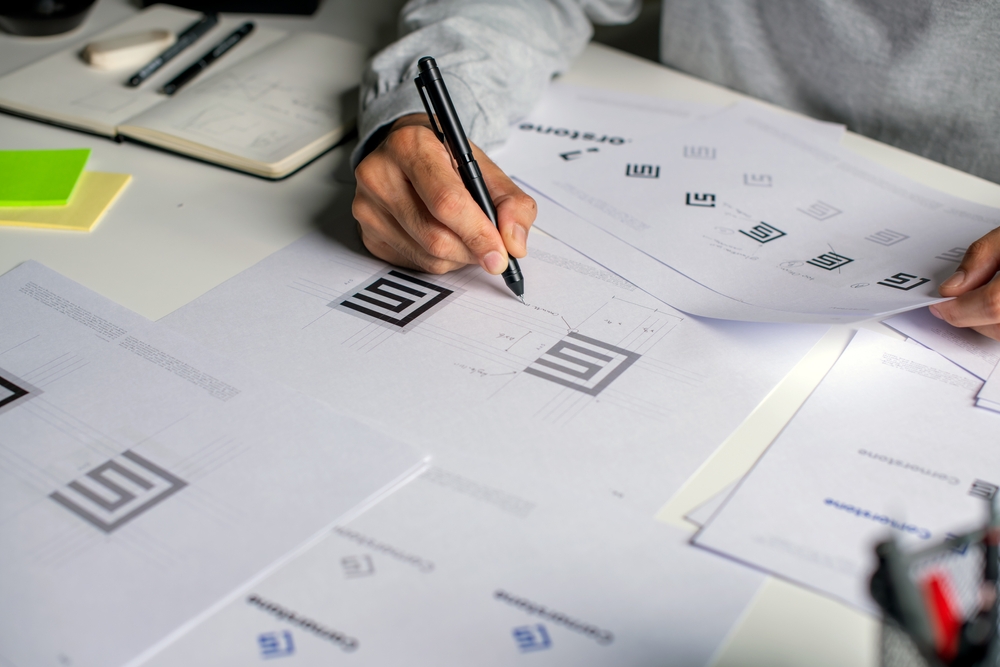 asian,graphic,designer,making,notes,on,logo,designs,,using,computers,